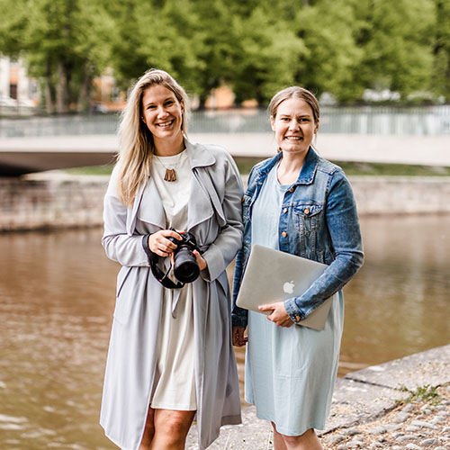 Linda and Satu with a camera and a laptop in front of Aura river in Turku