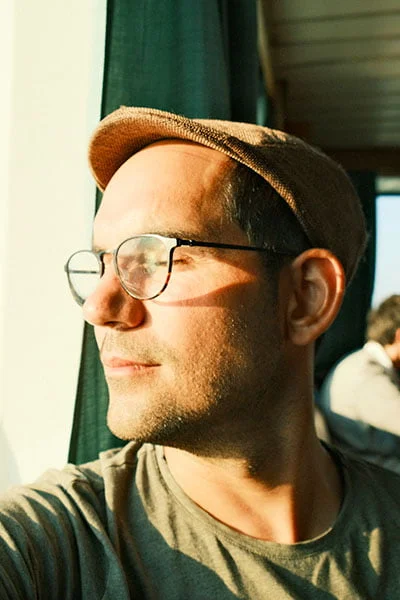 Aaron on a ferry looking trought the window to the sunny sea