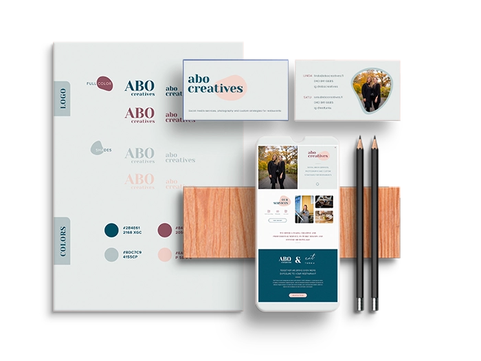 Mockup of a branding kit with business cards, webpage on phone, and sheet with branding elements