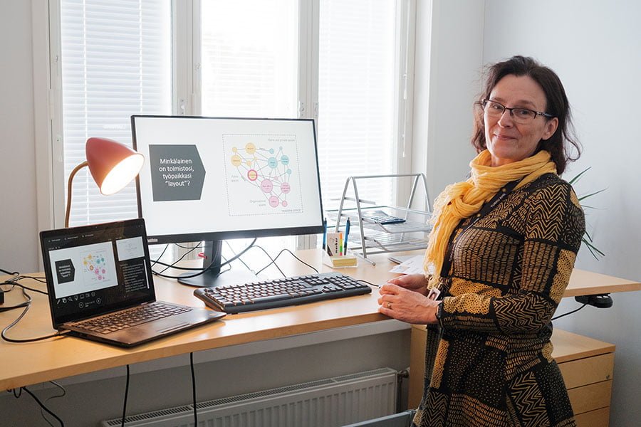 Ursula Hyrkkänen standing in front of a desk with two screens on Korpo island