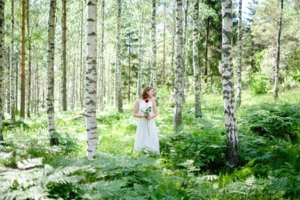 A young girl is in the forest during her graduation photoshoot, surrounded by beautiful birch trees.
