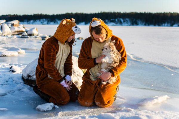 A couple dressed as bears holding their dog in a heavily snowy landscape.