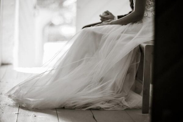 Black and white image of a wedding dress and the hands of the bride.
