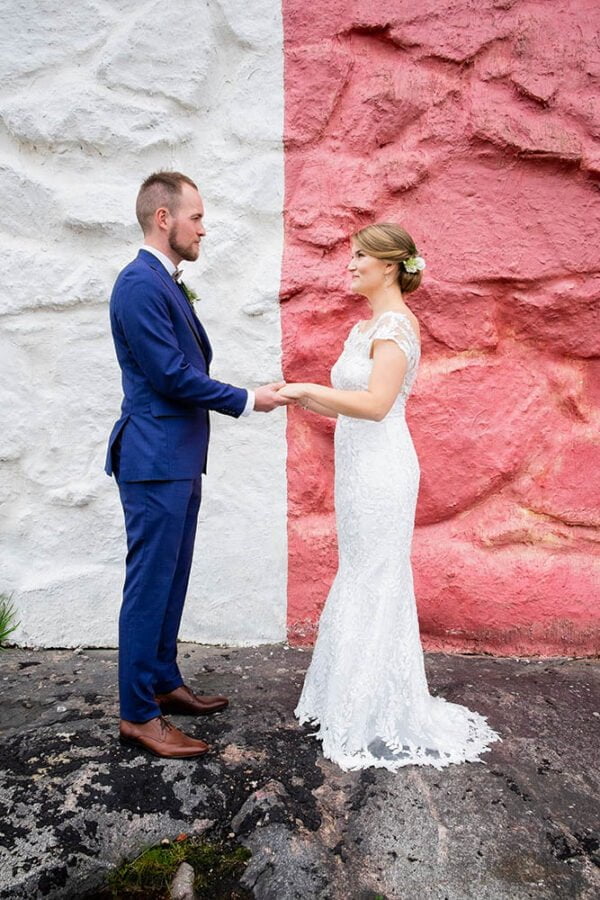 A wedding couple posing in front of a red and white wall.