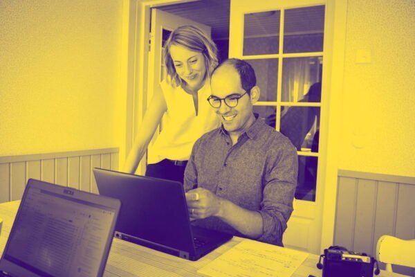 Duotone image of Aaron and Ida-Kajsa in front of a laptop reviewing a design