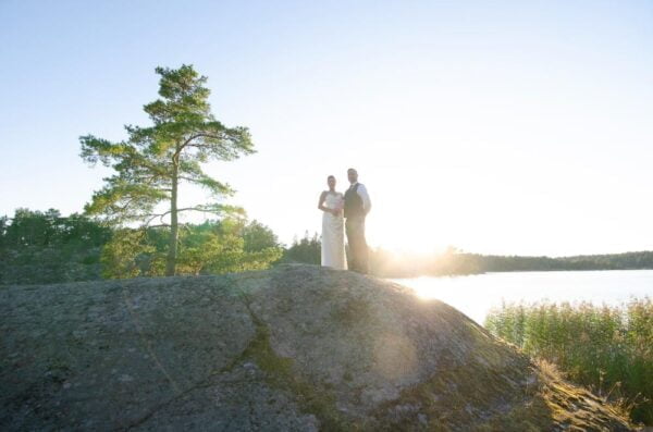 Wide perspective of the wedding couple on top of a rock with a striking sunset light.
