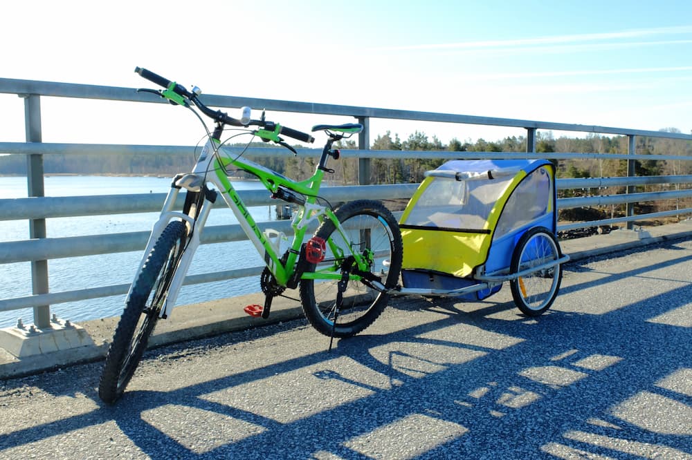 A mountain bike with a small trailer attached to it on a bridge over the sea